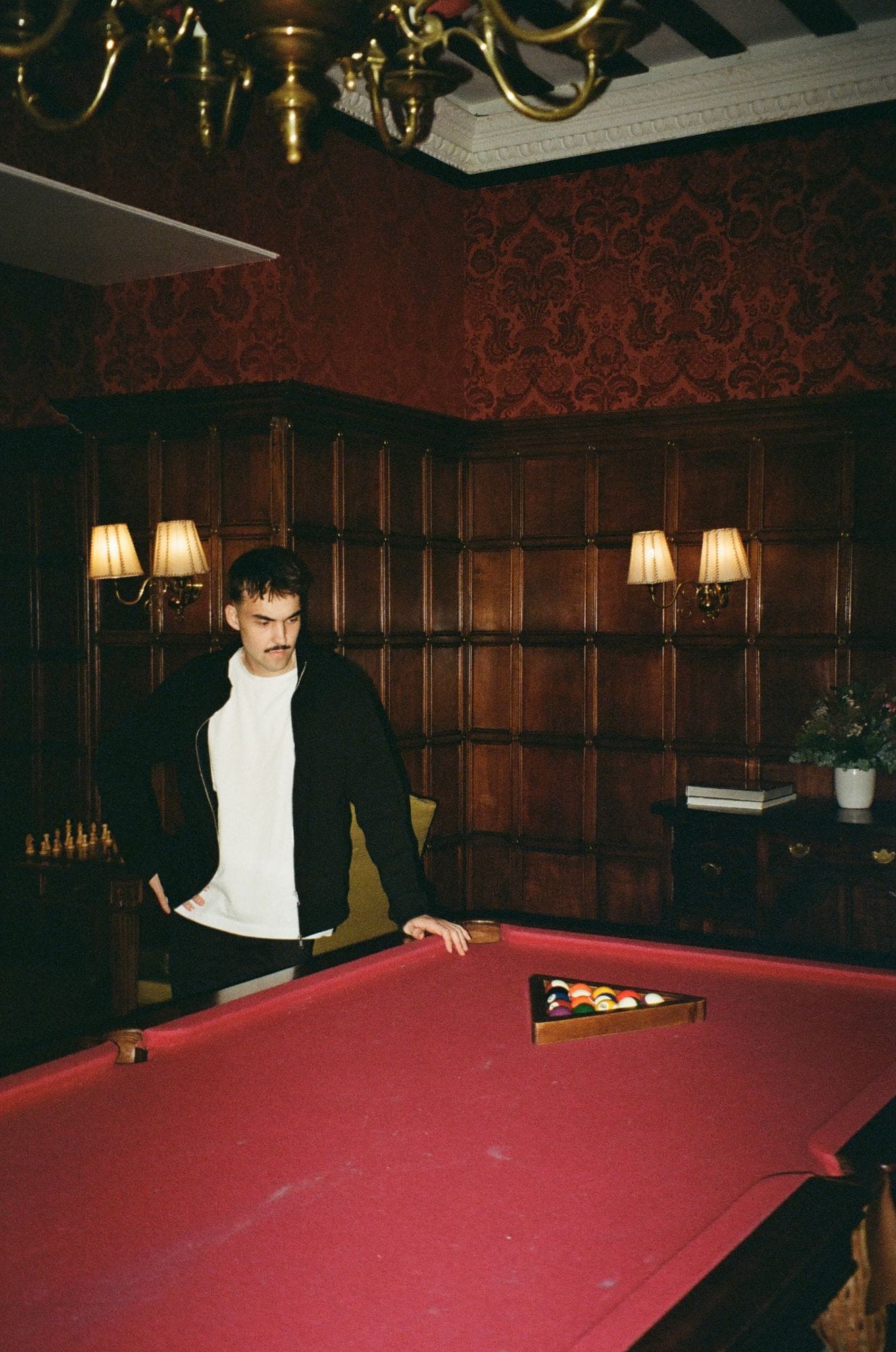 Debout près d'une table de billard, dans un salon aux boiseries sombres